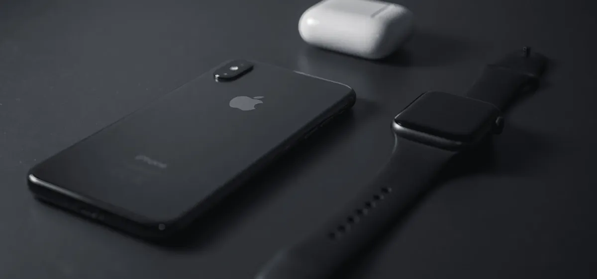 iPhone, Apple Watch, and AirPods on a dark surface, representing the Apple HealthKit ecosystem