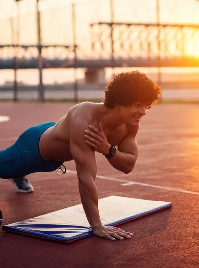 Man doing a one-arm push-up on a track at sunset