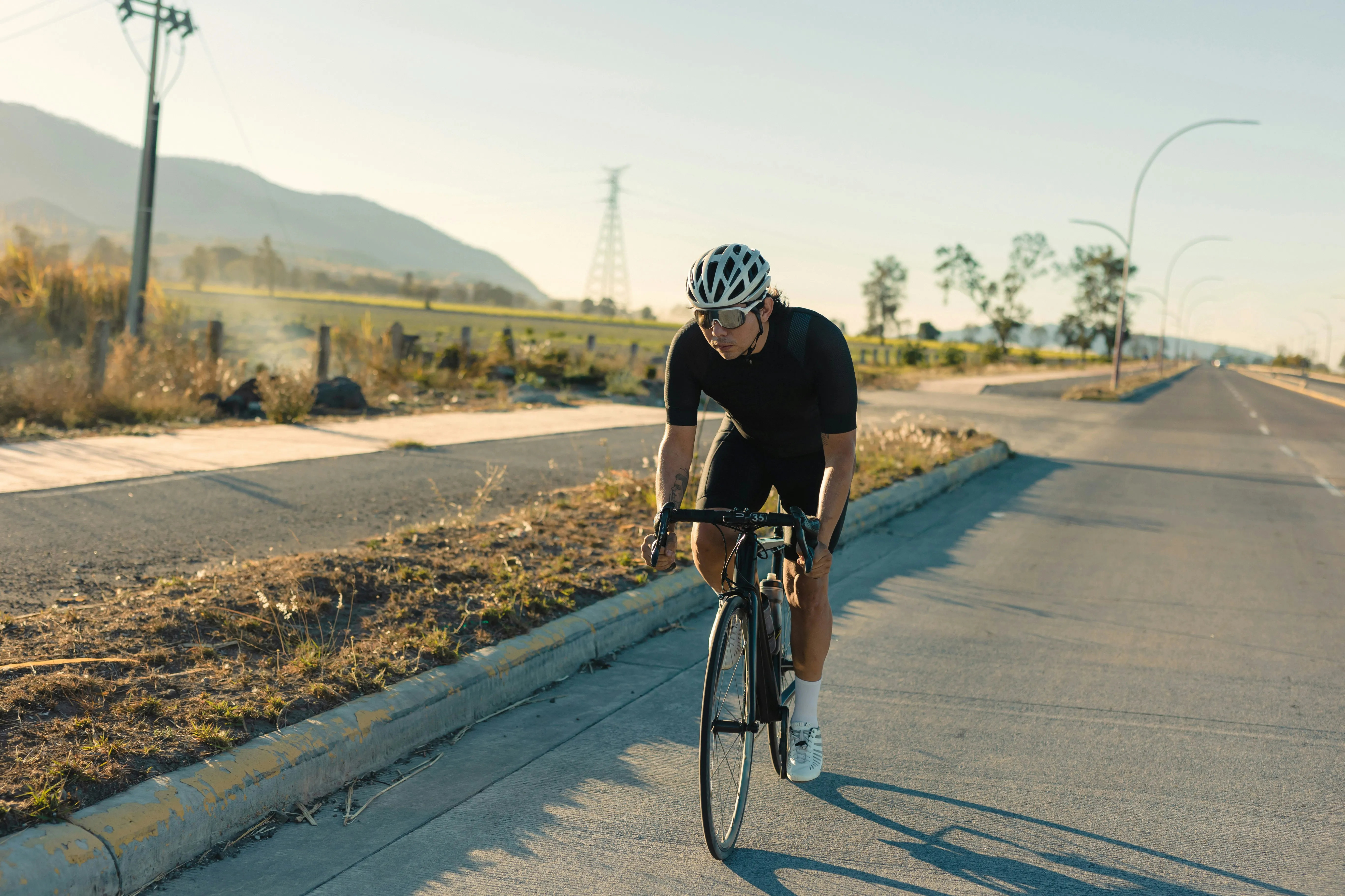 Road cyclist riding at sunset, building cycling training load toward peak performance