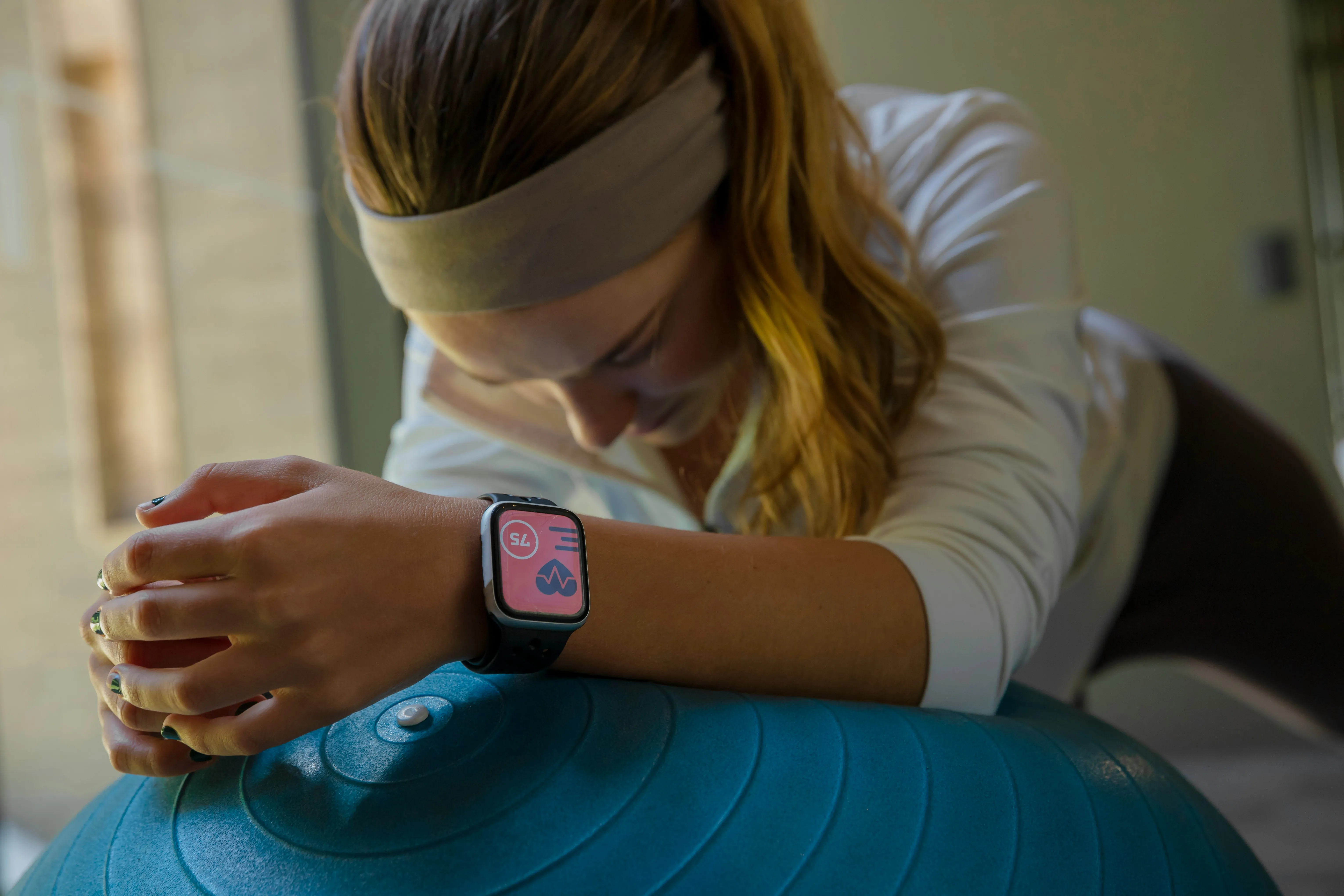 Woman checking her smartwatch fitness data while sitting on an exercise ball