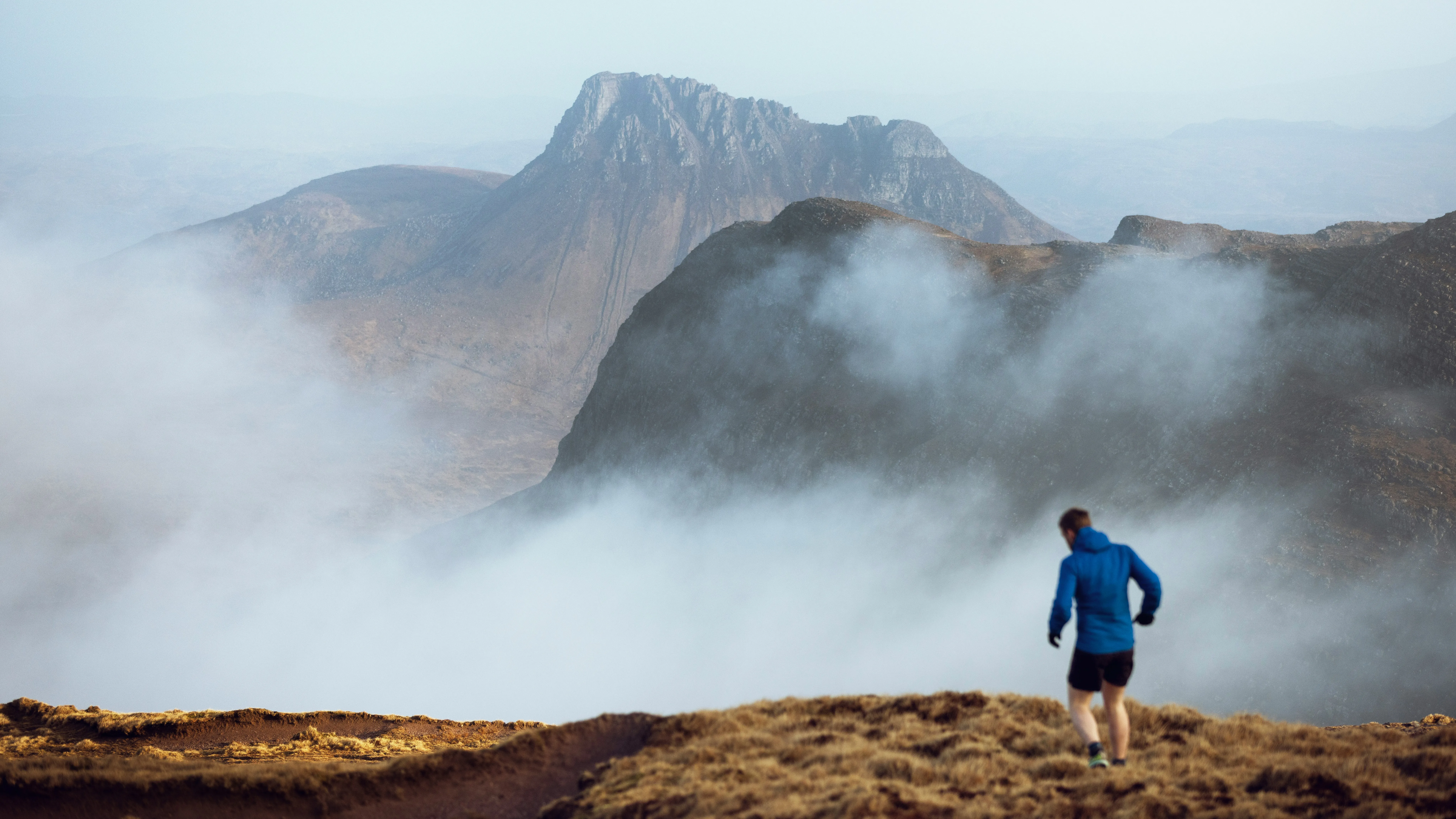 Runner on a misty mountain ridge, training in heart rate zones with dramatic scenery