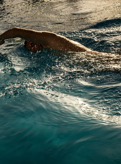 Swimmer doing freestyle in open water with golden light