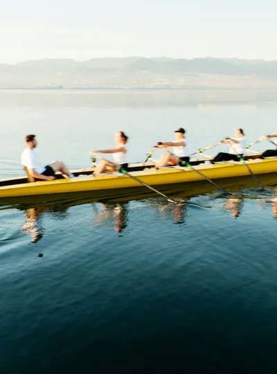 Rowing team on calm water at sunrise