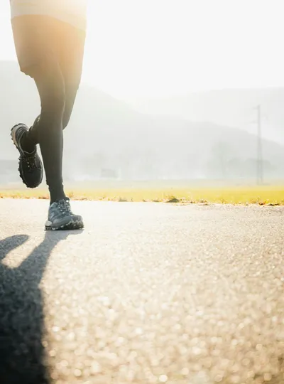 Runner on a road at sunrise with mountains in the background
