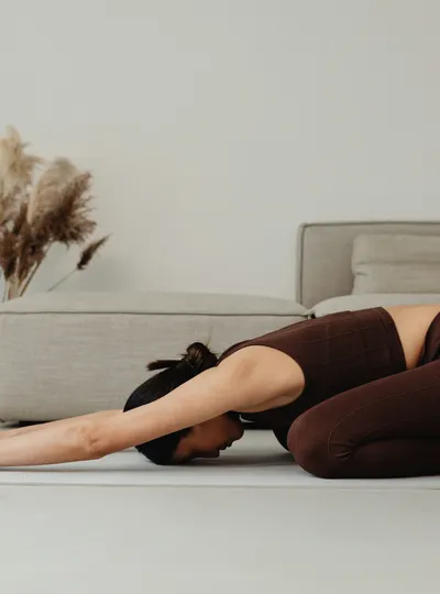Woman in child's pose on a yoga mat at home